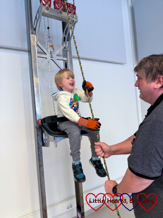 Thomas in a chair lift, pulling himself up using a pulley