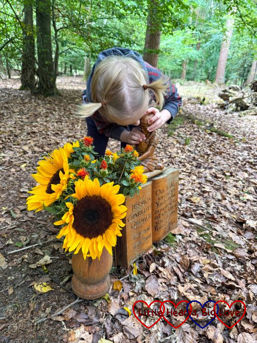 Thomas kissing the wooden statue at Jessica's forever bed with sunflowers in her wooden vase