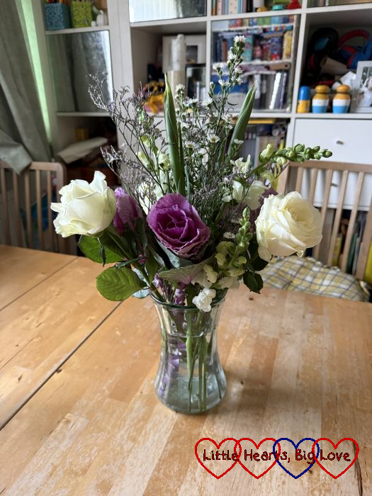 White roses, purple brassicas and other flowers in a vase