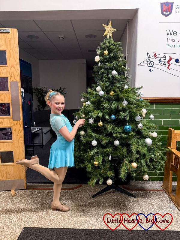 Sophie in her tap costume in front of a Christmas tree