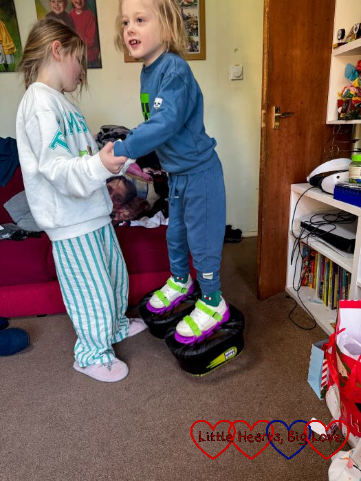 Thomas holding Sophie's hand while jumping in his moon shoes
