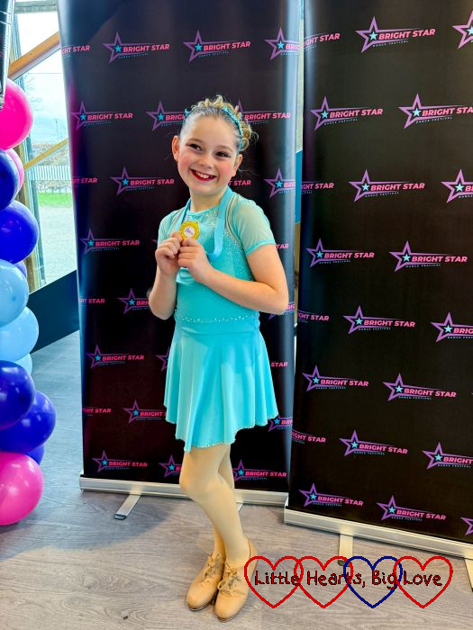 Sophie in her tap costume holding a gold medal