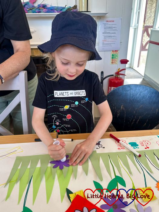 Thomas sticking paper flowers on a picture