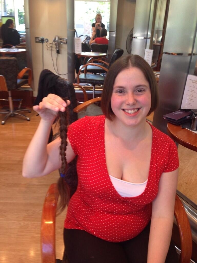 Me holding a long plait of hair having had my hair cut to donate to the Princess Trust