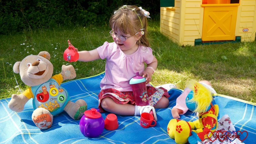 Jessica having a picnic with her toys in the garden