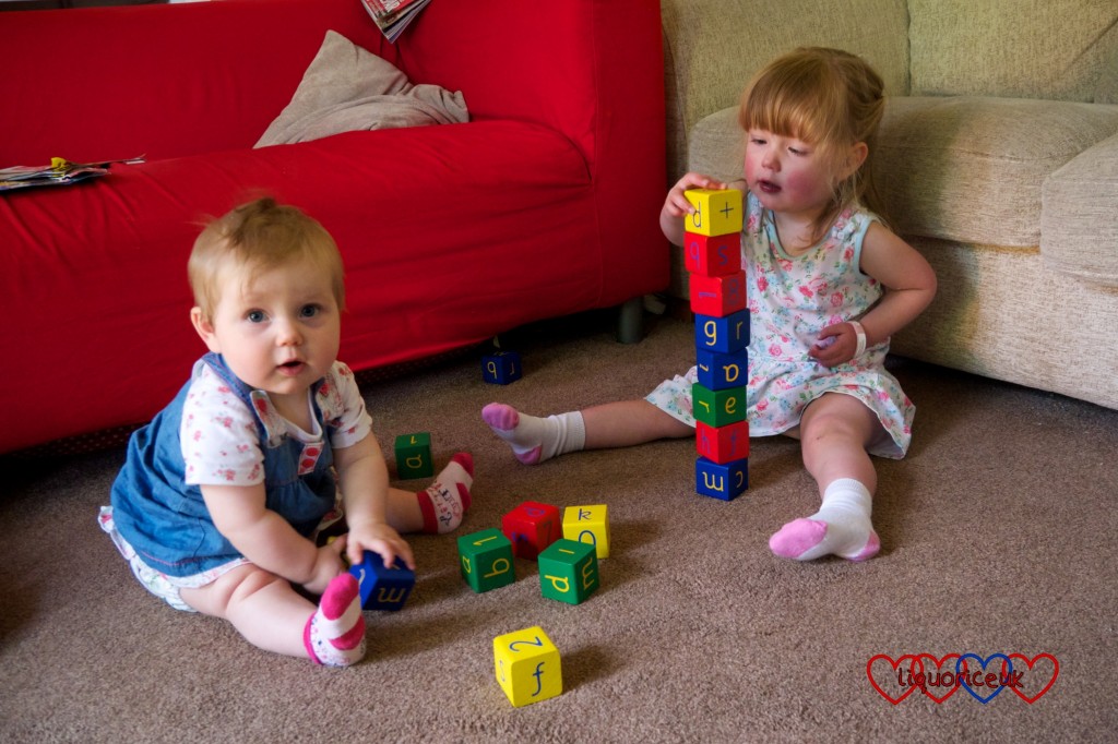 Sophie and Jessica sitting on the floor together playing with bricks