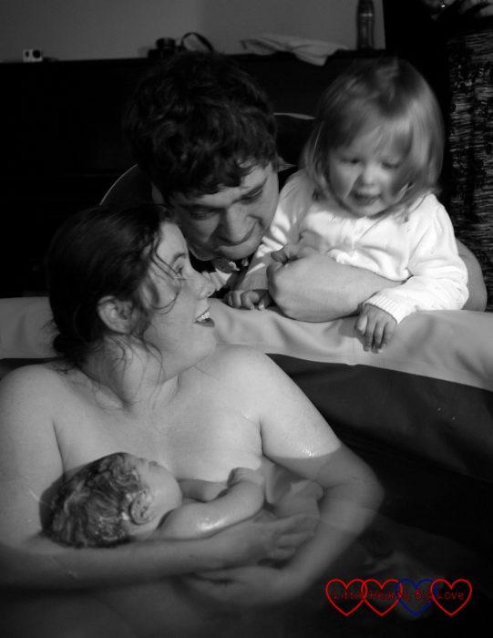 Me holding Sophie in the birthing pool with hubby and Jessica looking on