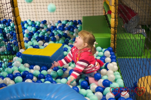 Jessica throwing balls in the air in a ball pit