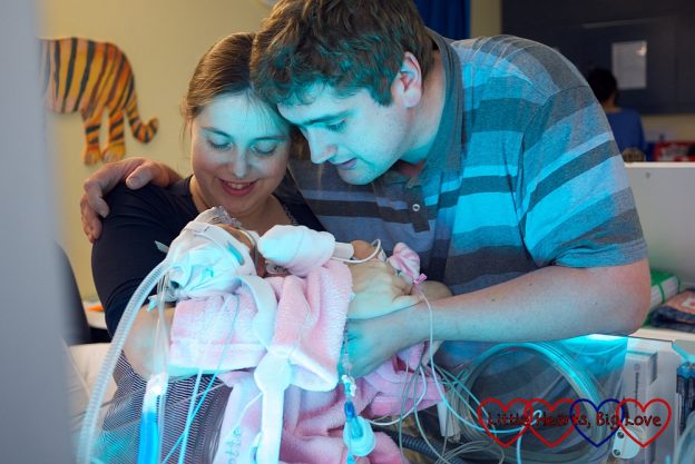 Me and hubby holding baby Jessica in intensive care. You can hardly see her for all the wires and tubes.