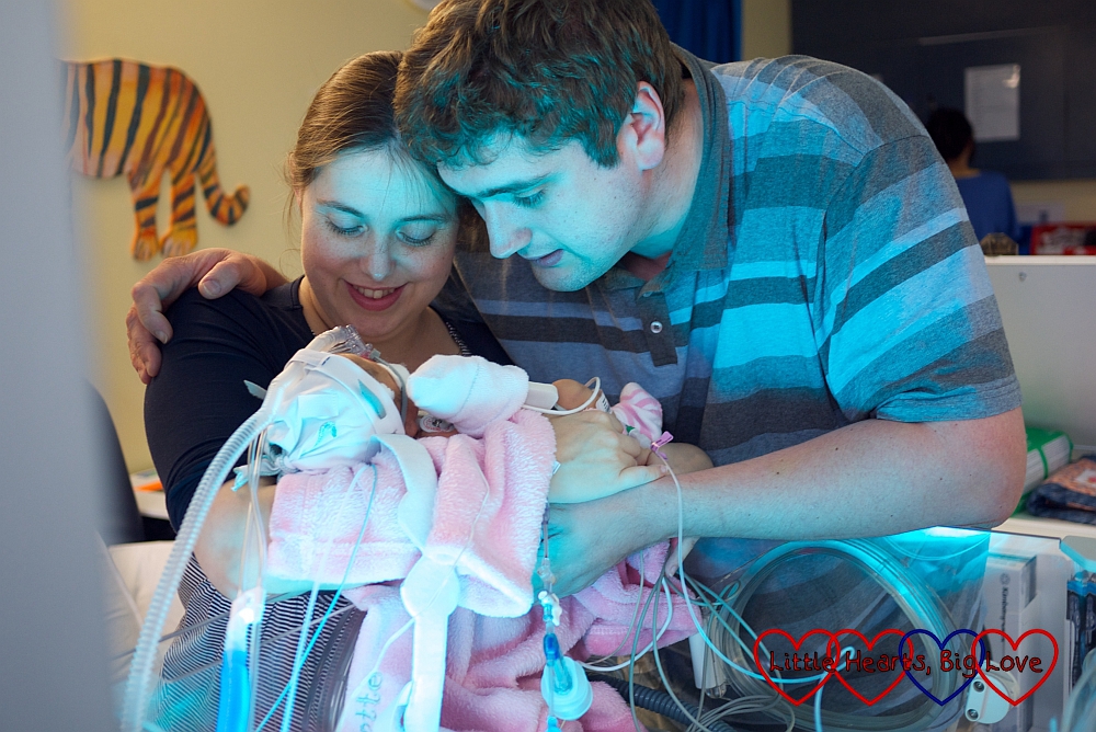 Me and hubby holding Jessica in intensive care. You can barely see her with all the wires and tubes covering her.