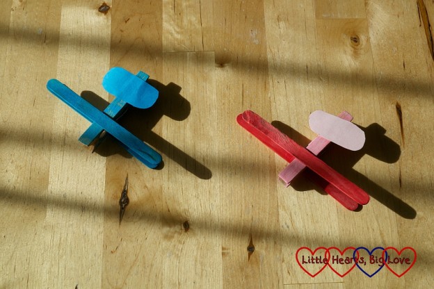 Two aeroplanes - one blue, one red - made from a peg and craft sticks