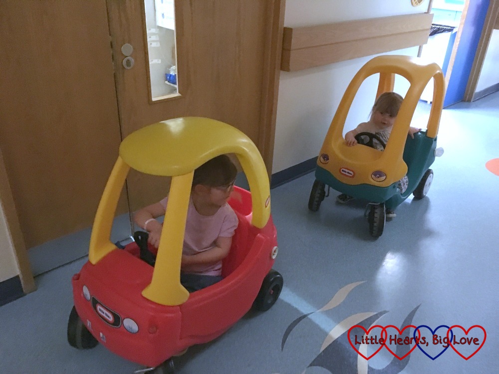 Jessica and Sophie chasing each other around the ward in the Little Tikes cars