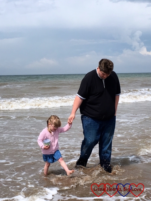 Jessica holding hands with her Daddy and both of them paddling in the sea with the bottoms of Daddy's trousers looking very soggy!