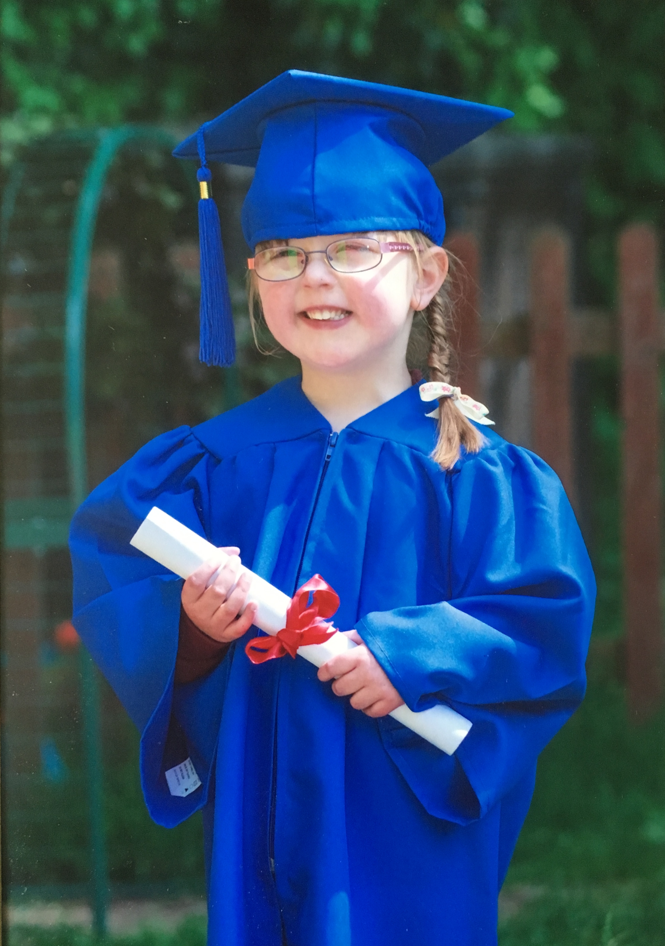 Jessica in her blue graduation gown in her preschool graduation photo