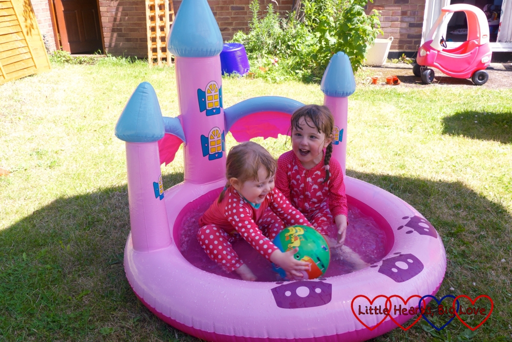 Jessica and Sophie splashing about with a ball in the paddling pool