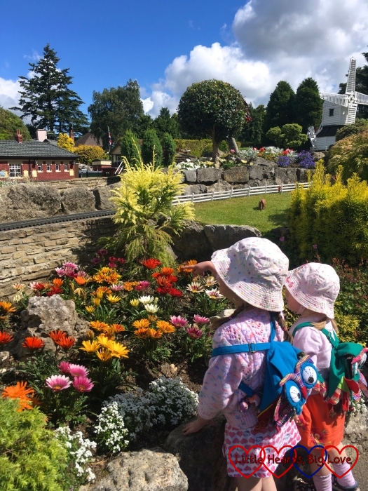 Jessica and Sophie standing looking up at the miniature railway with colourful pretty flowers in front of them