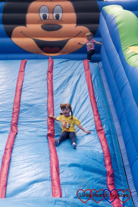 Jessica sliding down the giant inflatable slide with Sophie at the top