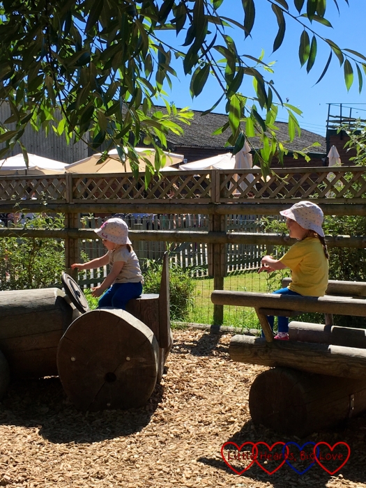 Sophie and Jessica riding a wooden tractor in one of the play areas at Odds Farm Park