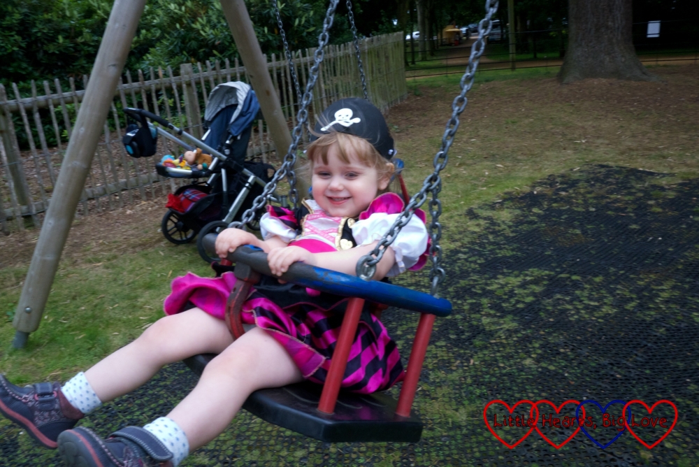 Sophie in her pirate outfit swinging on the toddler swing