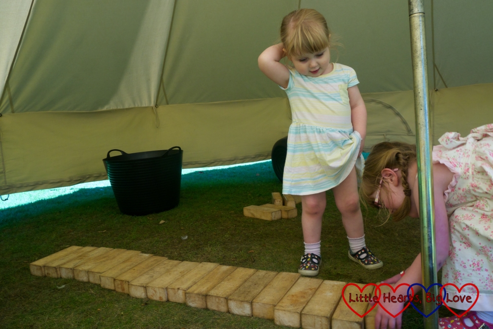 Sophie making a xylophone with the wooden blocks