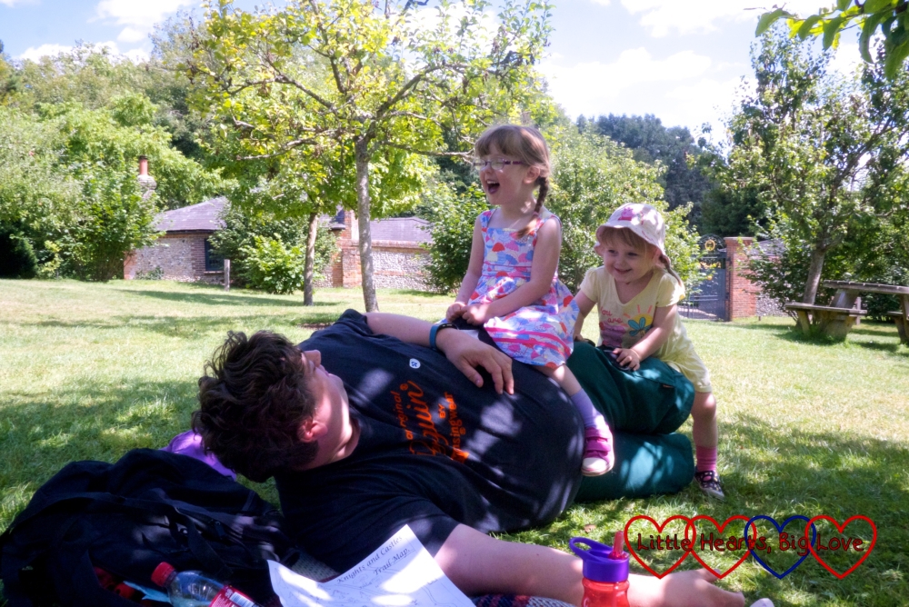 Hubby lying in the sunshine with the girls sitting on him