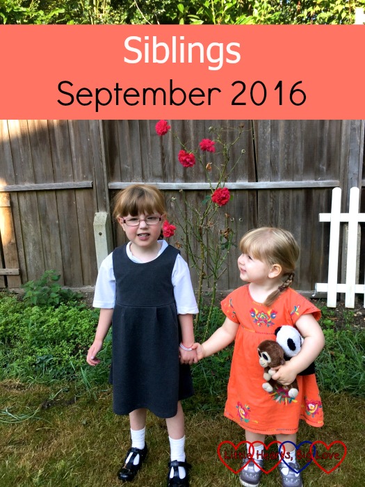 Jessica in her school uniform and Sophie in an orange dress holding hands in front of the roses in the garden - Siblings: September 2016
