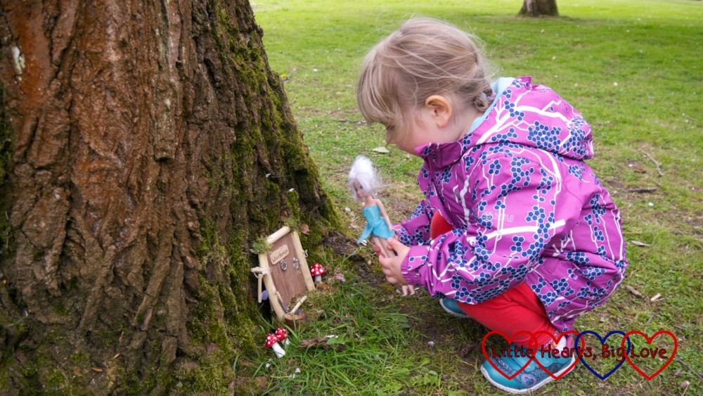 Sophie looking at one of the fairy doors with her Periwinkle fairy doll