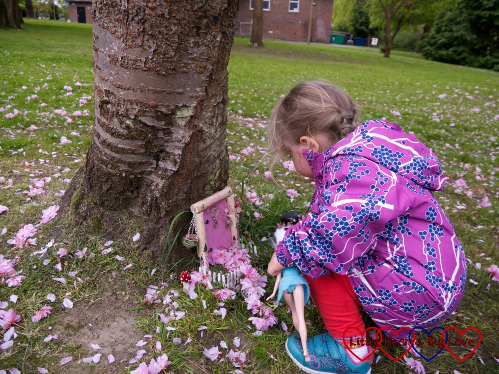 Sophie looking at a pink fairy door surrounded by fallen blossom