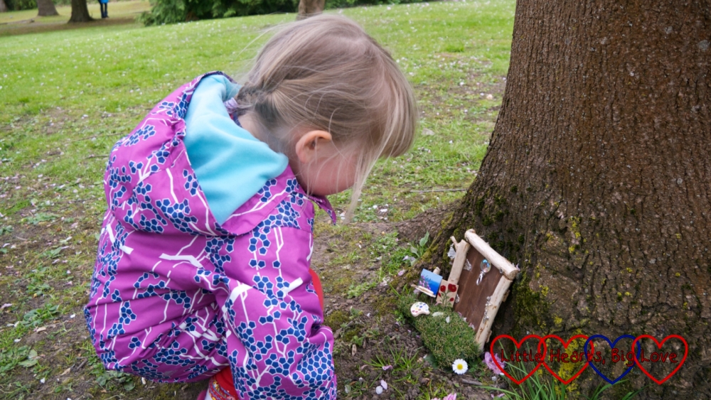 Sophie looking at a fairy door with miniature paintings outside