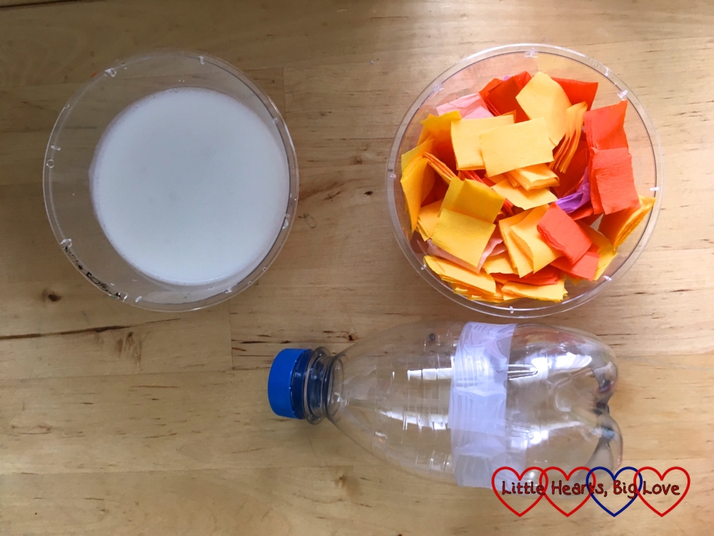 A bowl of PVA glue, a bowl of tissue paper strips and a plastic bottle with the middle discarded and the top and bottom taped together