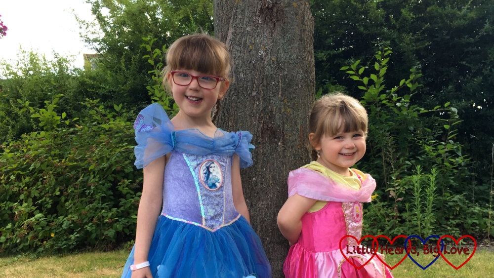 Jessica and Sophie standing by a tree wearing princess dresses