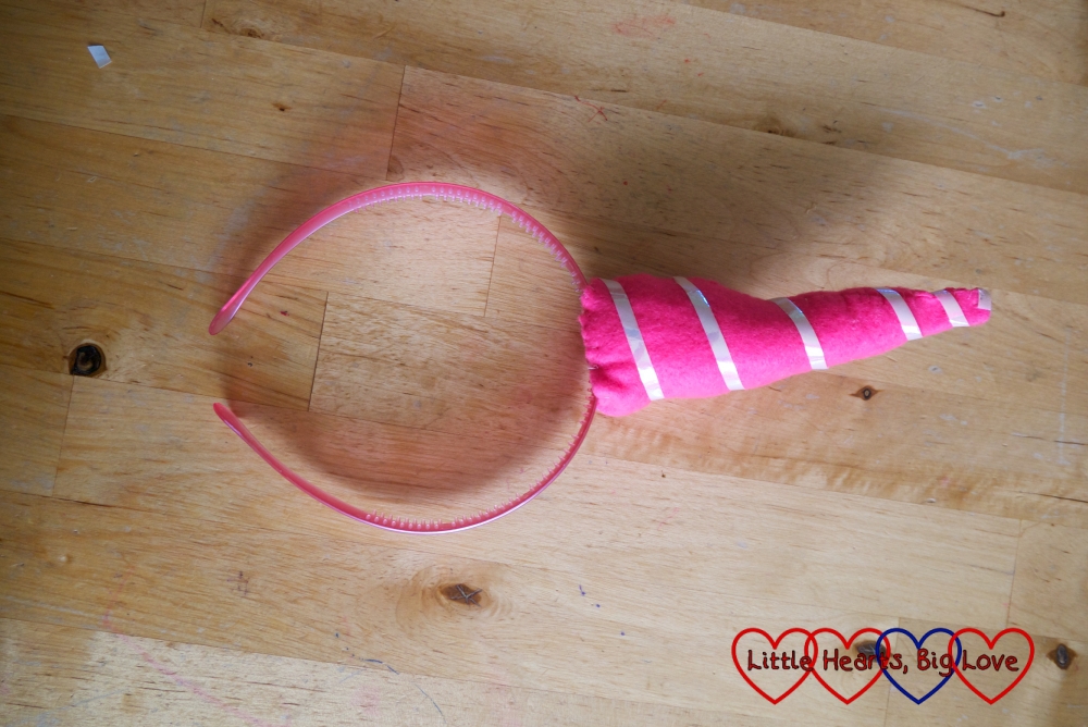 A pink felt unicorn horn attached to a pink headband