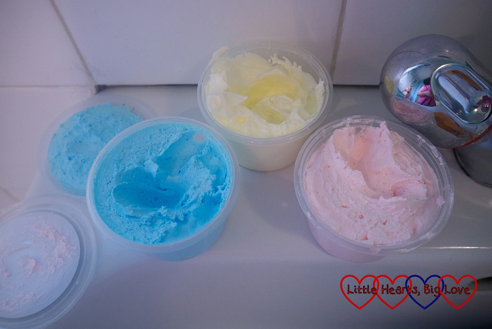 Open soap paint pots in blue, yellow and pink with some of the soap scooped out