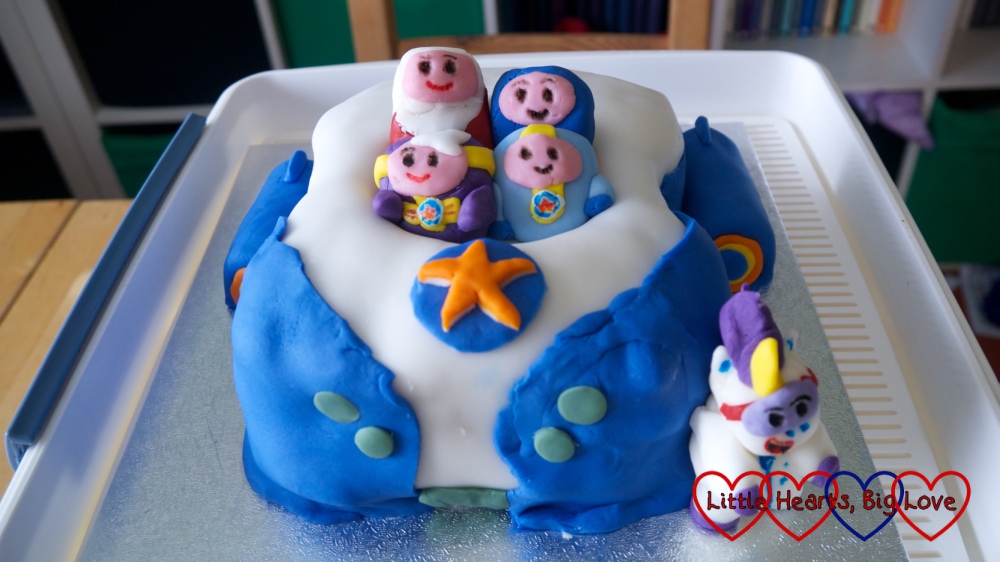 A Go-Jetters Vroomster cake with the four Go Jetters sitting inside the vroomster and Ubercorn standing next to it