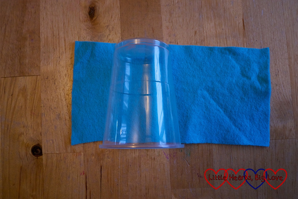 A plastic cup with a piece of blue felt behind it