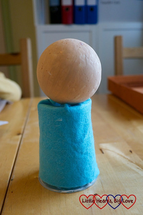 A polystyrene ball resting on the top of a felt-covered cup