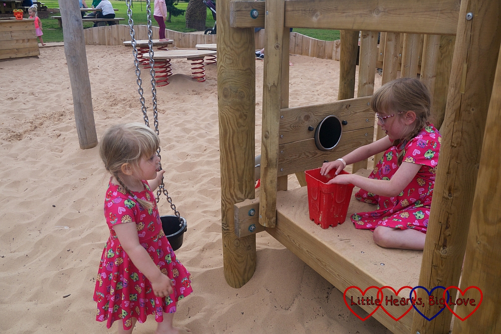 Sophie and Jessica filling buckets of sand in the sand play area at Trentham Gardens