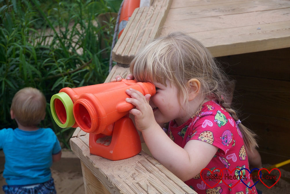 Sophie looking through the binoculars on the pirate ship in the play area at Trentham Gardens
