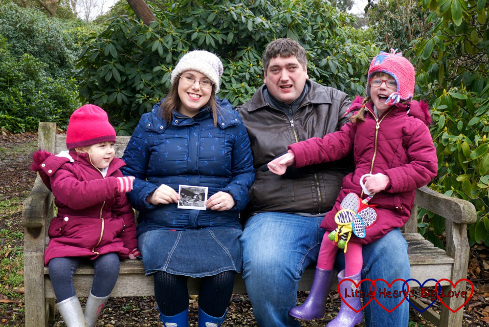 Sophie, me, hubby and Jessica sitting on a bench with me holding a scan photo