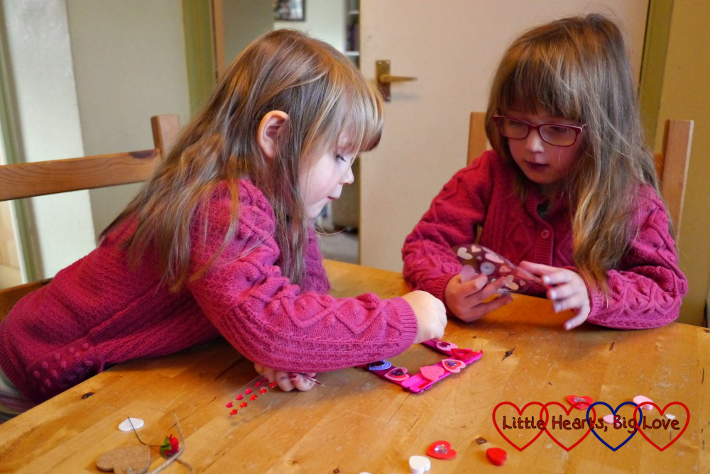 Jessica and Sophie decorating the craft stick frame with heart shapes and stickers