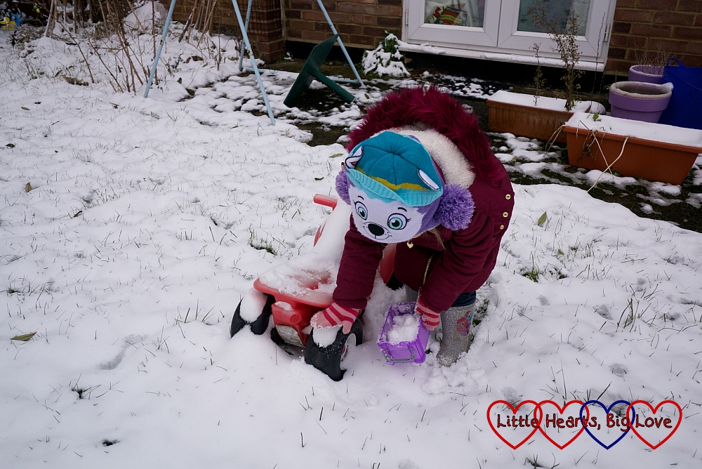 Sophie collecting snow from her toy bike and putting it into a box