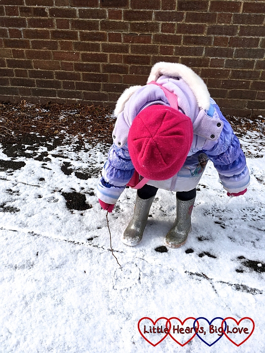 Sophie drawing a face in the snow with a stick