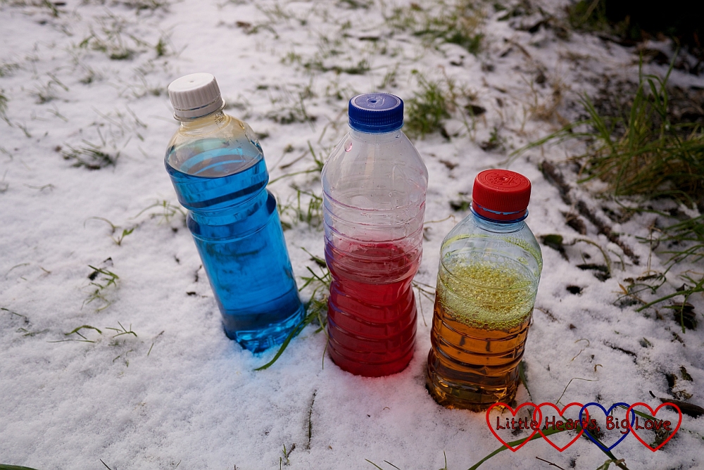 Three clear bottles filled with food colouring and water - one blue, one red and one yellow