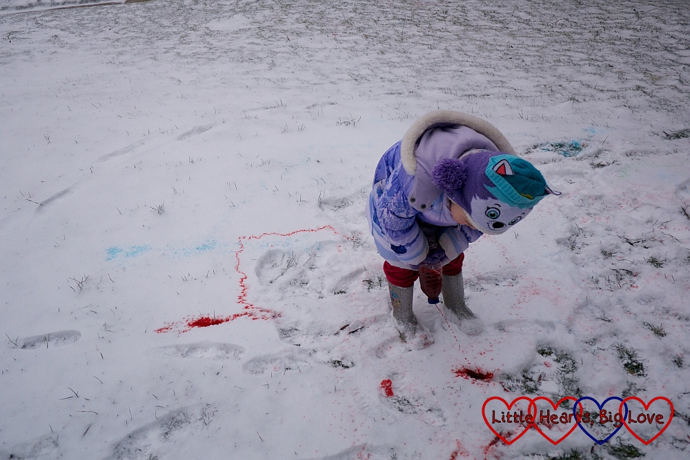 Sophie squirting red food colouring and water on the snow