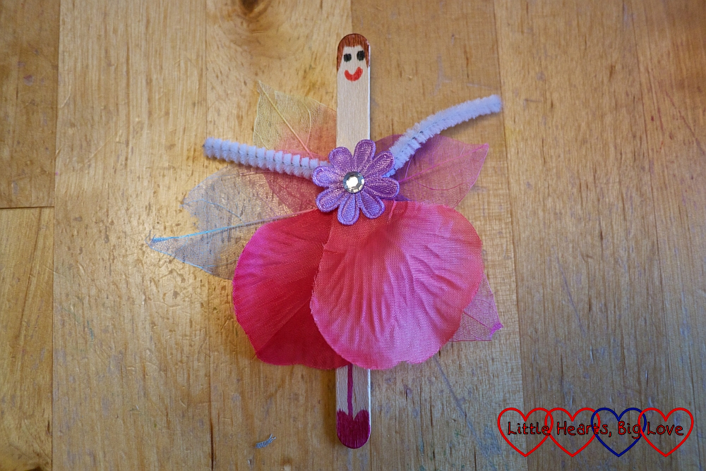 The craft stick fairy with a face drawn on