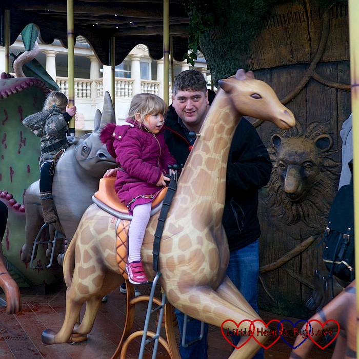 Sophie riding a rocking giraffe on the Adventure Tree carousel