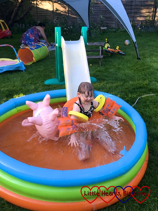 Sophie sliding down a slide into a paddling pool