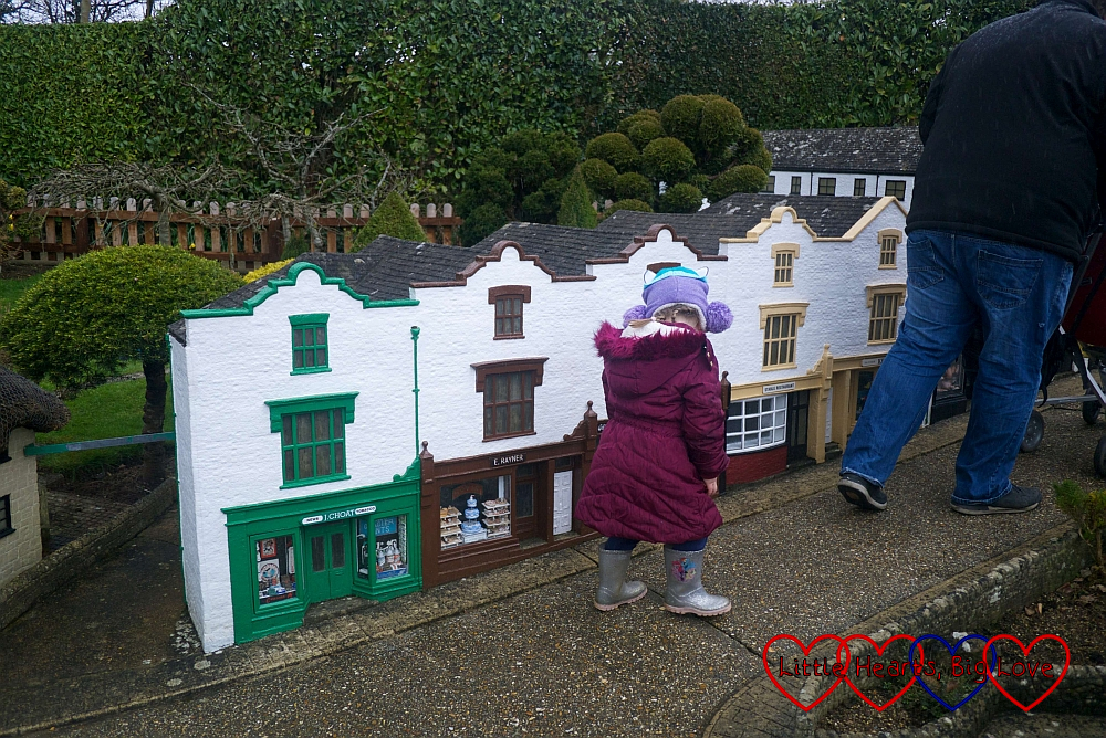 Sophie walking past some of the shops in the model village