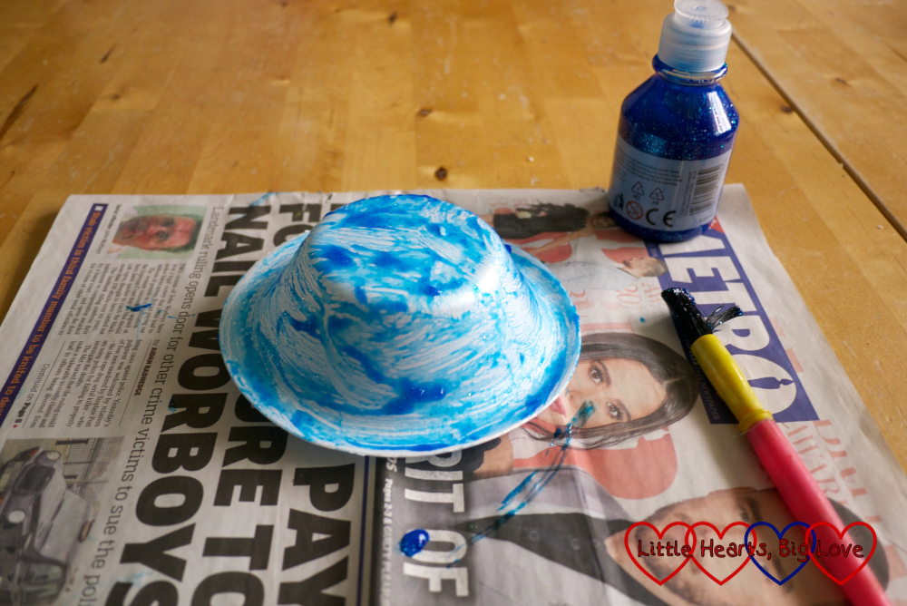 Painting the outside of the paper bowl with blue glitter paint