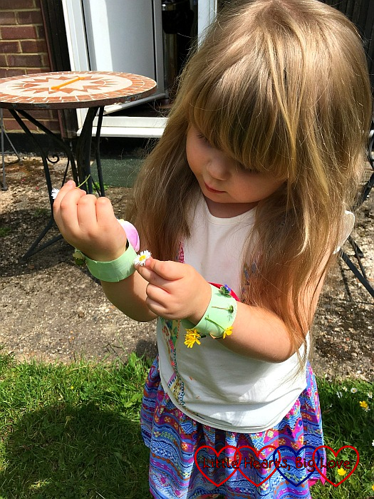Sophie sticking daisies to her nature bracelet